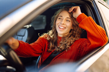 Portrait of young woman is driving a car and smiling. Car travel, lifestyle concept.