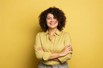 Fototapeta na wymiar Portrait of a happy young woman with arms crossed over yellow background