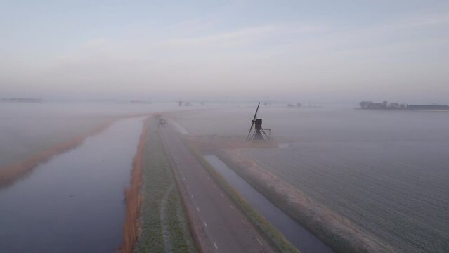 Aerial view of a traditional windmill in misty countryside at dawn, Netherlands