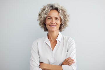 Portrait of smiling mature businesswoman standing with arms folded and looking at camera