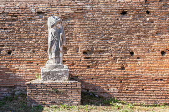 Ancient roman statue in ruins in front of a brick wall in Italy