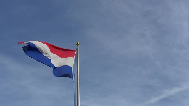 Netherlands Flag. Close up of Dutch flag flying in Holland in the wind in front of a light blue sky. Slow motion clip.