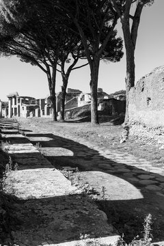 Black and white photo showing the road along ancient roman buildings at archaeological park in Italy