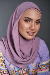 Beautiful female model wearing modern kebaya batik , an Asian traditional dress for Muslim woman isolated over grey background. Stylish Muslim female hijab fashion lifestyle portraiture concept.