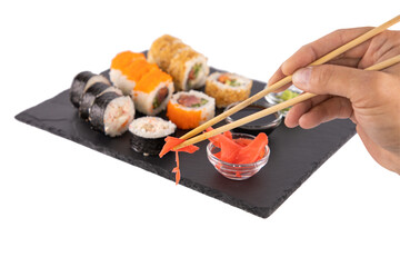 Male hand holding ginger with sushi chopsticks.