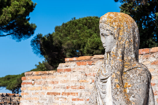Close-up on profile of ancient roman statue in ruins portraiting a young woman wearing a veil
