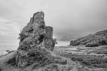 A black and white image of the ruins of a castle along the coast of Isle of Raasay, Scotland.