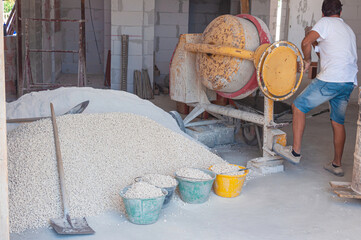 Cement mixer machine at construction site, tools and sand