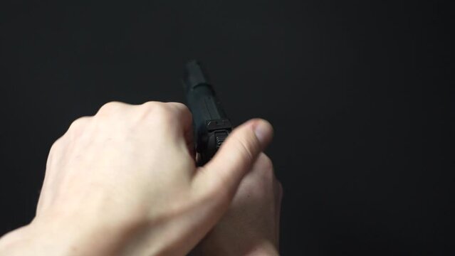 Loading a handgun, inserting a ammunition clip and aiming with one hand &ndash; view from behind