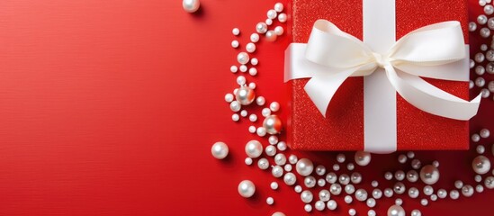Red gift box with pearl decoration on white background viewed from above.