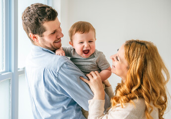 young beautiful family couple with baby boy on gray studio