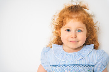 Little cute girl in a dress with redhead. The child is 2 years old.