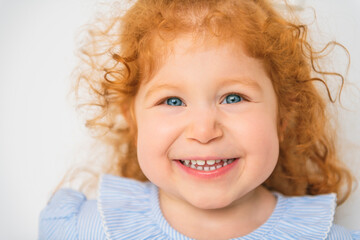 Little cute girl in a dress with redhead. The child is 2 years old.