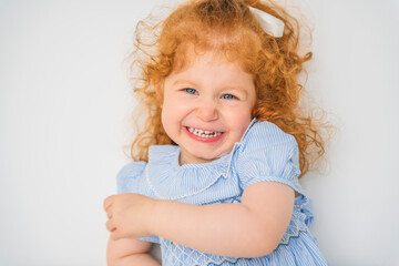 Little cute girl in a dress with redhead. The child is 2 years old.