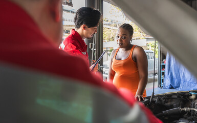 Japanese car mechanic explaining to black female customer in auto repair shop