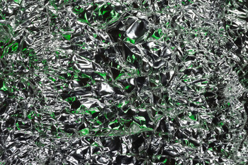 Glaring surface. Crumpled aluminum foil. Crumpled background. Colored glitter. Selective focus
