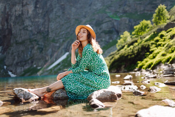 Beautiful woman in dress enjoys on a mountains along a lake. Fashion, beauty, lifestyle, travel concept.