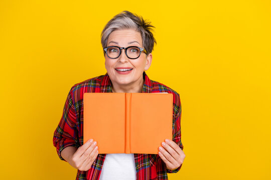 Photo of cheerful astonished lady hold opened book toothy smile empty space isolated on yellow color background