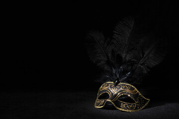 Carnival gold mask with feathers on black background.
