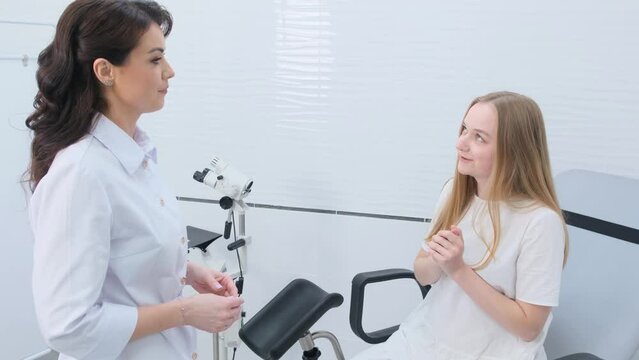 the gynecologist listens attentively to the patient sitting in the gynecological chair during the appointment.