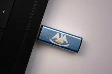 usb flash drive in notebook computer with the national flag of louisiana state on gray background.