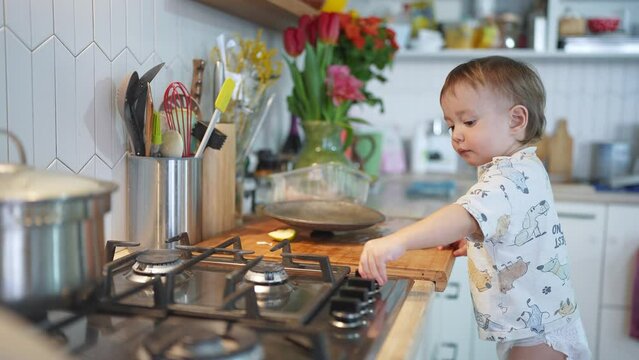 baby plays in the kitchen. happy family kid concept. baby son plays lifestyle in the kitchen with fireweed baby climbed onto a chair near the kitchen stove, plays with tongs, kitchen dream tools