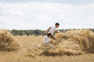 Children run through a haystack in a field in summer