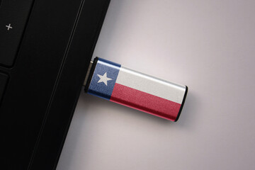 usb flash drive in notebook computer with the national flag of texas state on gray background.