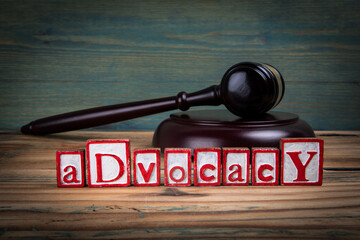 ADVOCACY. Red alphabet letters and judge's gavel on wooden background. Laws and justice concept