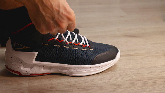 Close-up of black and white basketball shoes. Men's hands are tying the laces. Preparing for a training session or a walk.