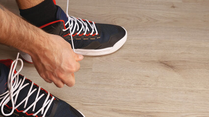A close-up showing the process of tying the laces on a pair of sneakers, emphasizing the manual dexterity and intricate details of this task.