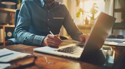 A man sitting at a desk with a laptop and pen. Suitable for business and technology concepts