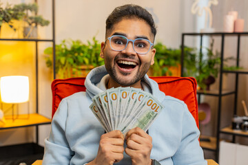 Successful happy rich business Indian man counting money cheering up with high profits, celebrate...