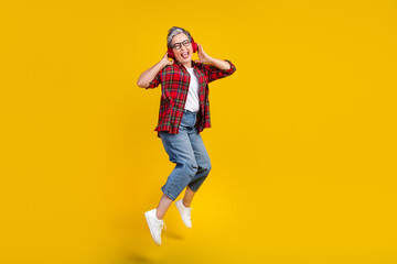 Fototapeta na wymiar Full length photo of energetic nice lady jump hands touch headphones empty space isolated on yellow color background