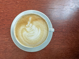 Cappuccino with foam and coffee art on top on a wooden table top