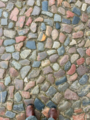Colorful cobblestone road framed by a person’s feet