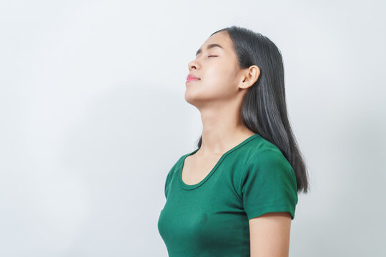 Happy and calm Asian girl is seen enjoying a pleasant aroma, taking deep breaths of fresh air in isolation.