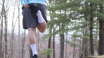 A man stretching before exercising on a forest path
