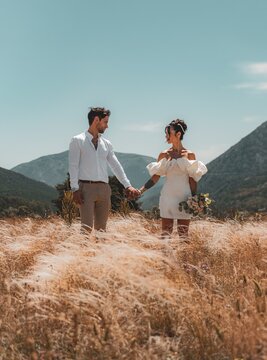 wedding photography, moment betxeen a bride and groom as they hold hands against a backdrop of majestic moutains and golden wheat fields