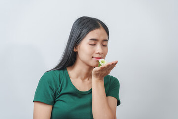 Beautiful young Asian woman in green t-shirt inhales the fragrance of white chrysanthemum flowers,...