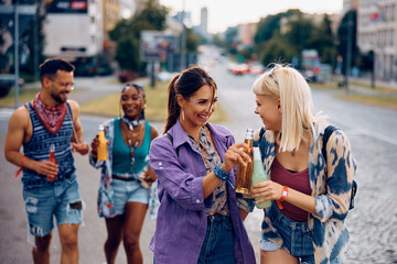 Cheerful women toasting with drinks while going with friends on music summer festival.