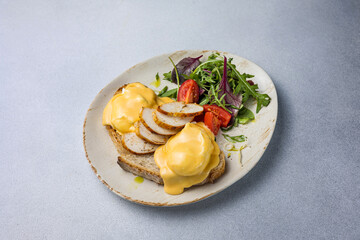 Eggs benedict with cheese and salad on a plate