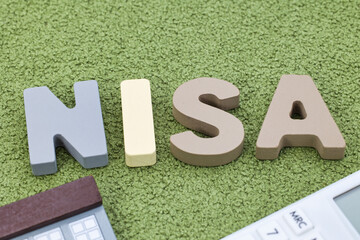 緑の絨毯に置かれたNISAの文字ブロック