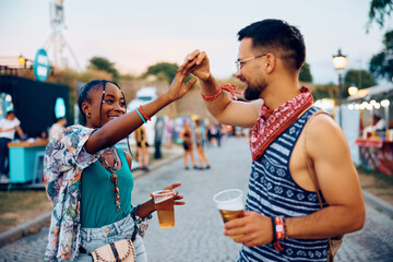 Carefree couple dancing and having fun during open air music festival in summer.