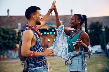 Happy couple of festival goers dancing during outdoor summer concert.