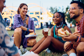 Happy black woman and her friends enjoying in beer and burgers during summer music festival. - Powered by Adobe