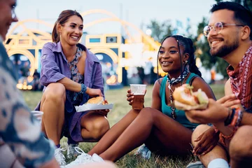 Fotobehang Happy black woman and her friends enjoying in beer and burgers during summer music festival. © Drazen