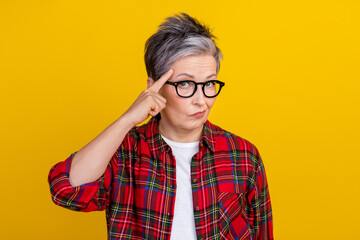 Photo of aged lady finger touch head temple think about it mocking empty space isolated on yellow color background