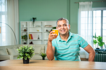 Indian mid age handsome man drinking fresh juice in a glass