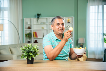 Indian mid age man eating potato chips